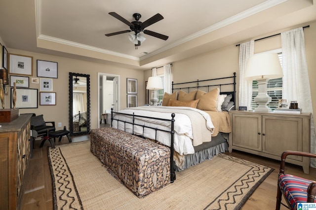 bedroom with a tray ceiling, ornamental molding, ceiling fan, and light wood-type flooring