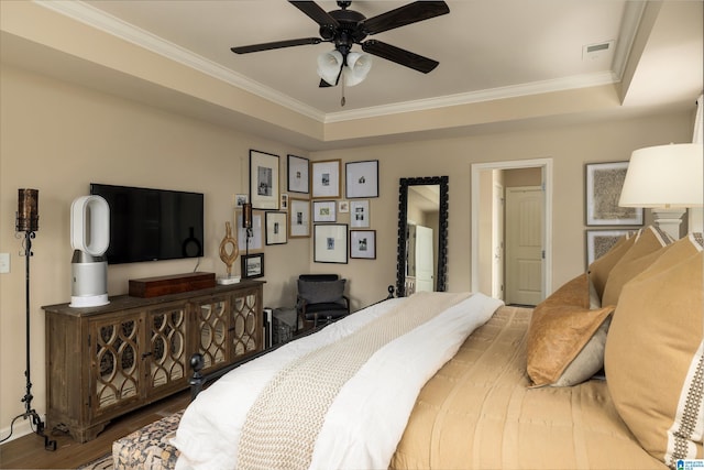 bedroom with wood-type flooring, ornamental molding, a raised ceiling, and ceiling fan