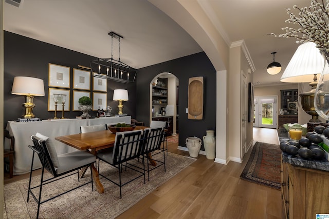 dining space featuring ornamental molding, wood-type flooring, and built in features