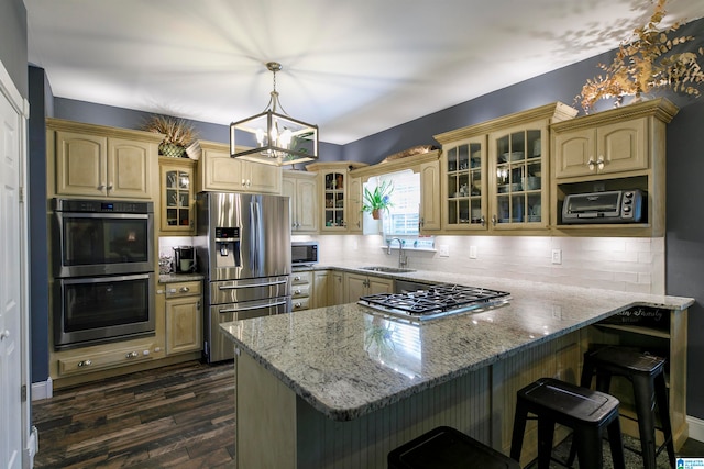 kitchen featuring tasteful backsplash, stainless steel appliances, light stone countertops, hanging light fixtures, and sink