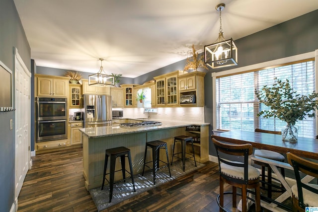 kitchen with backsplash, light stone counters, dark hardwood / wood-style floors, stainless steel appliances, and light brown cabinetry