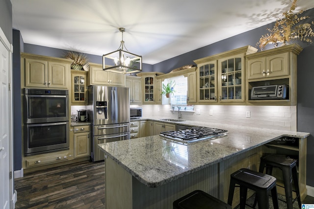 kitchen featuring stainless steel appliances, a kitchen bar, light stone countertops, and kitchen peninsula