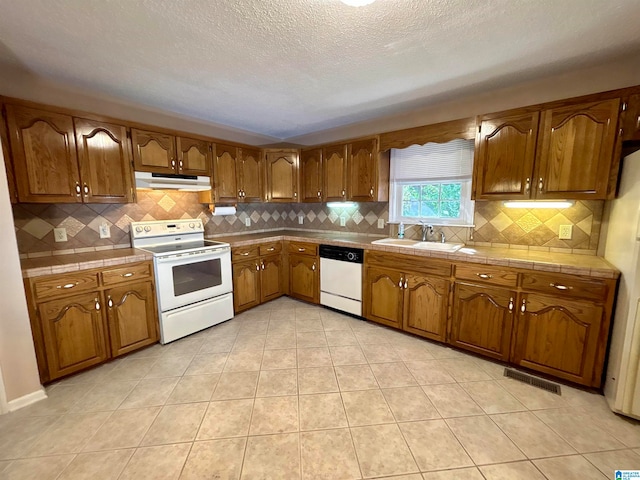 kitchen featuring white appliances, light tile patterned floors, tile countertops, sink, and tasteful backsplash