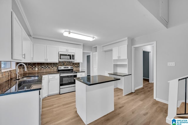 kitchen with white cabinets, backsplash, light hardwood / wood-style floors, appliances with stainless steel finishes, and sink