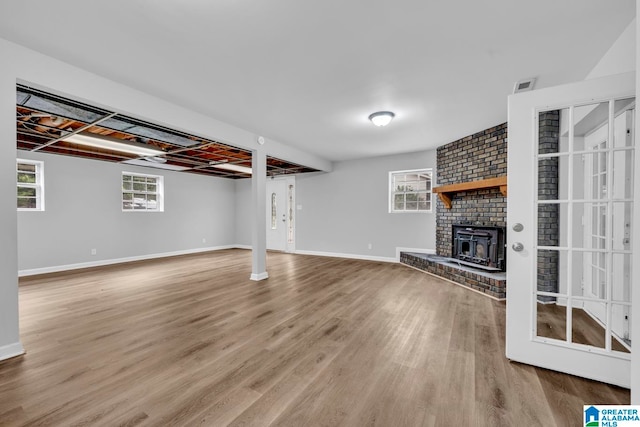 unfurnished living room featuring plenty of natural light, brick wall, a fireplace, and hardwood / wood-style flooring