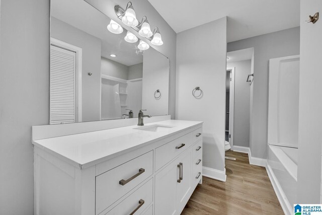 full bathroom featuring a notable chandelier, bathtub / shower combination, toilet, vanity, and wood-type flooring