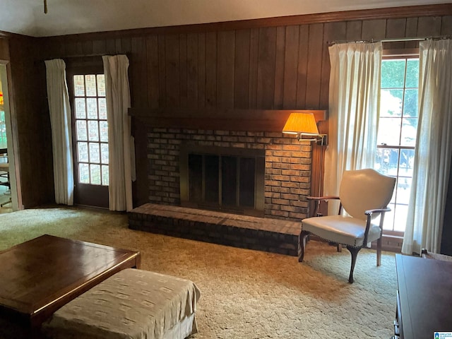 living room featuring carpet floors, wood walls, and a brick fireplace