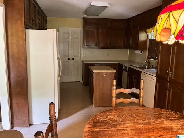 kitchen with sink, light tile patterned floors, dark brown cabinetry, and white appliances