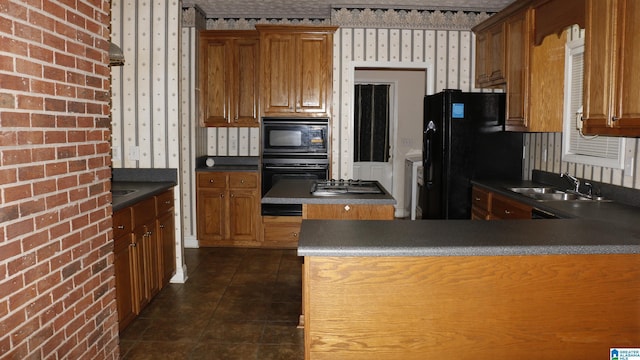 kitchen featuring dark countertops, a sink, brown cabinetry, black appliances, and dark tile patterned flooring