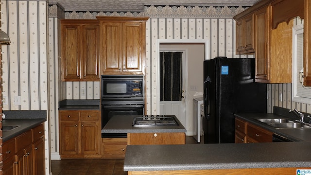 kitchen featuring a sink, dark countertops, black appliances, and wallpapered walls