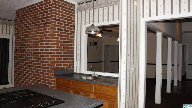 interior space featuring dark countertops, black stovetop, wallpapered walls, and a sink