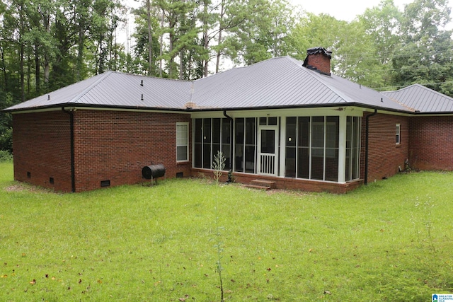 back of property with a chimney, crawl space, a lawn, brick siding, and metal roof