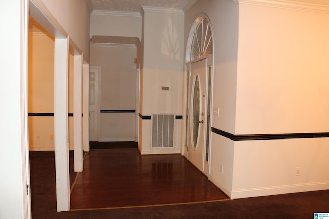 hallway with visible vents, ornamental molding, baseboards, and wood finished floors