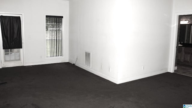 unfurnished room with dark colored carpet, visible vents, and baseboards