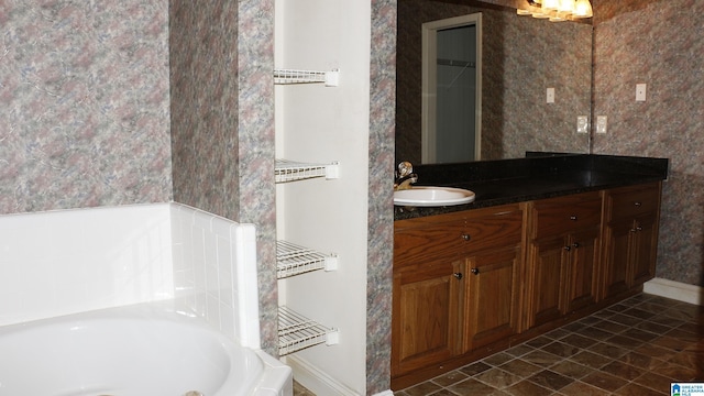 full bath featuring a bath, vanity, and baseboards