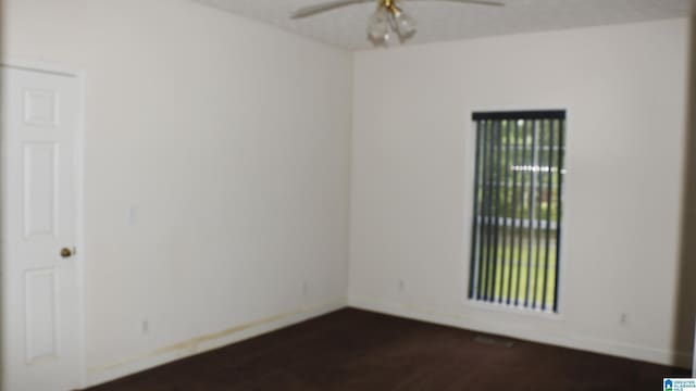 empty room featuring baseboards, dark wood-type flooring, and a ceiling fan