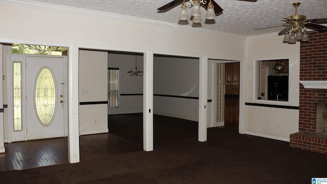 foyer entrance featuring a ceiling fan, a textured ceiling, ornamental molding, and a fireplace