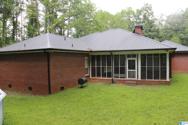 back of property with brick siding, a lawn, a chimney, metal roof, and crawl space