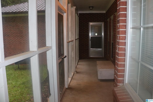 corridor featuring brick wall and unfinished concrete floors