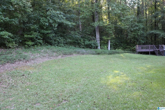 view of yard with a forest view and a wooden deck