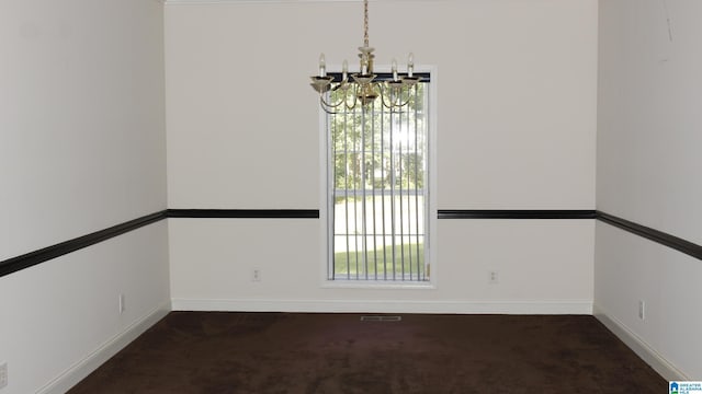 carpeted spare room with a notable chandelier, visible vents, and baseboards