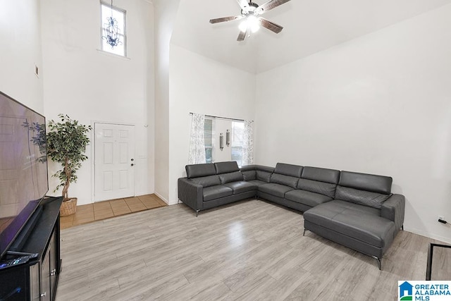 living room featuring light hardwood / wood-style floors, a wealth of natural light, ceiling fan, and a towering ceiling