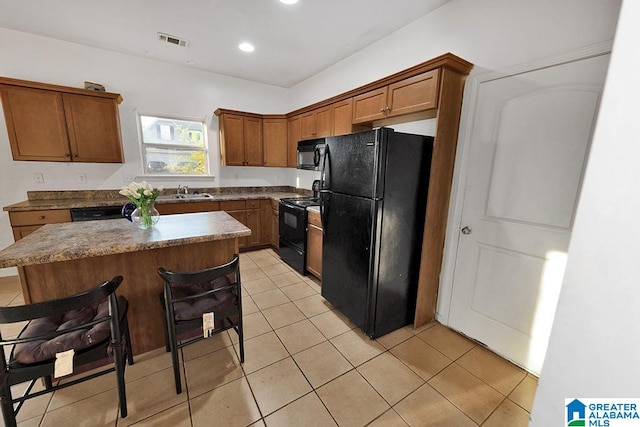 kitchen with a center island, black appliances, sink, and light tile patterned floors