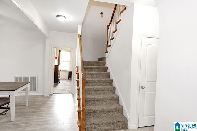 stairway with light hardwood / wood-style floors