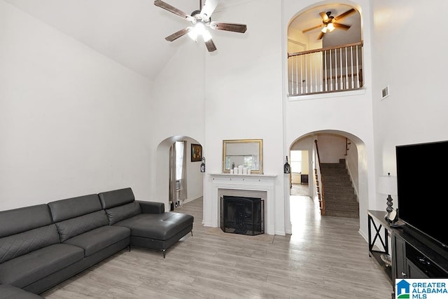 living room with light hardwood / wood-style floors, ceiling fan, and a high ceiling