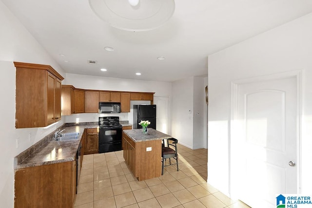 kitchen with black appliances, sink, a center island, light tile patterned floors, and a kitchen breakfast bar