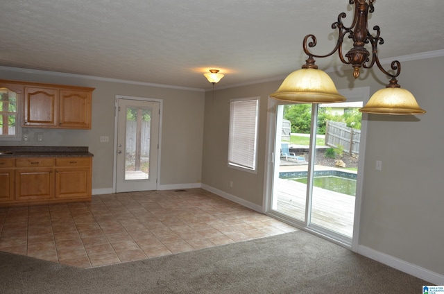 kitchen featuring hanging light fixtures, crown molding, and plenty of natural light