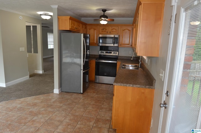 kitchen with tile patterned floors, stainless steel appliances, sink, and ornamental molding