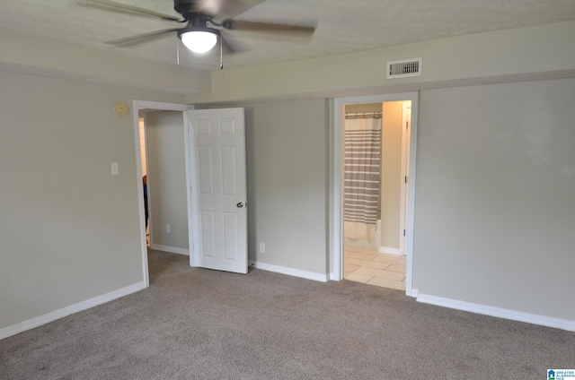 unfurnished bedroom featuring ceiling fan, connected bathroom, light carpet, and a textured ceiling