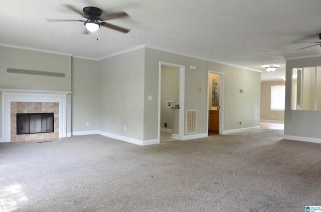 unfurnished living room featuring light carpet, a tiled fireplace, crown molding, and ceiling fan