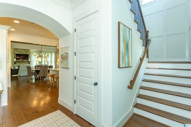 staircase featuring hardwood / wood-style flooring, a notable chandelier, and ornamental molding