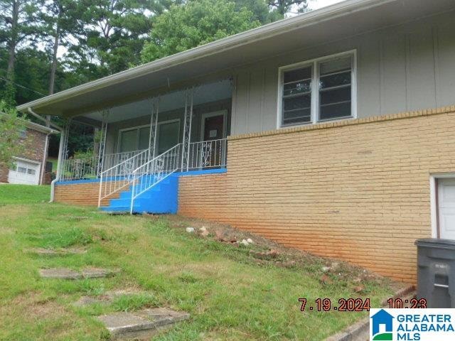 view of side of property featuring covered porch and a lawn