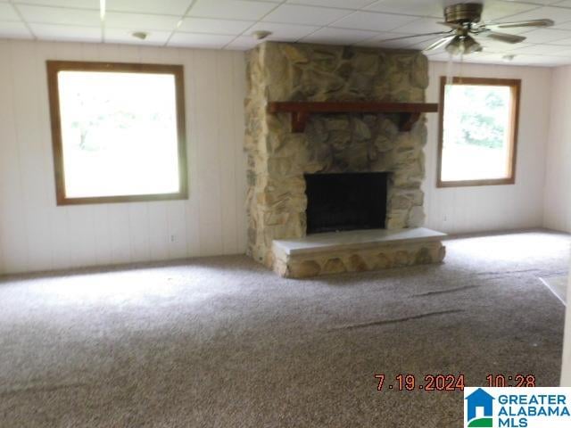 unfurnished living room with a fireplace, a drop ceiling, a wealth of natural light, and ceiling fan