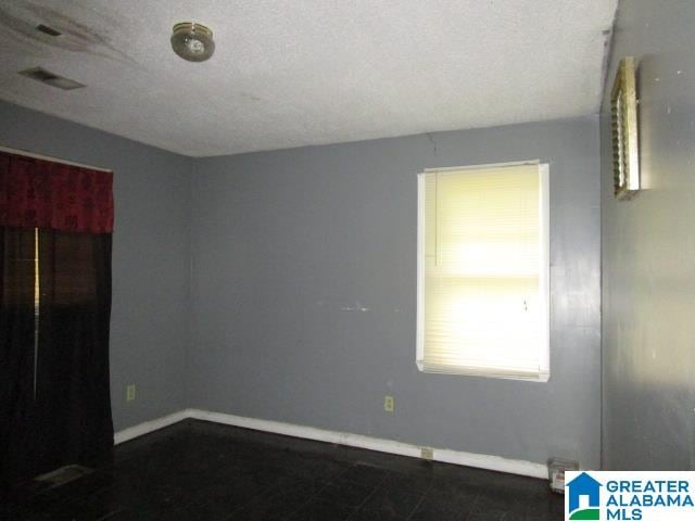 tiled empty room featuring a textured ceiling