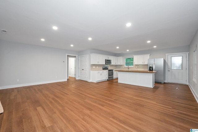 kitchen with white cabinetry, light hardwood / wood-style floors, a center island, and appliances with stainless steel finishes