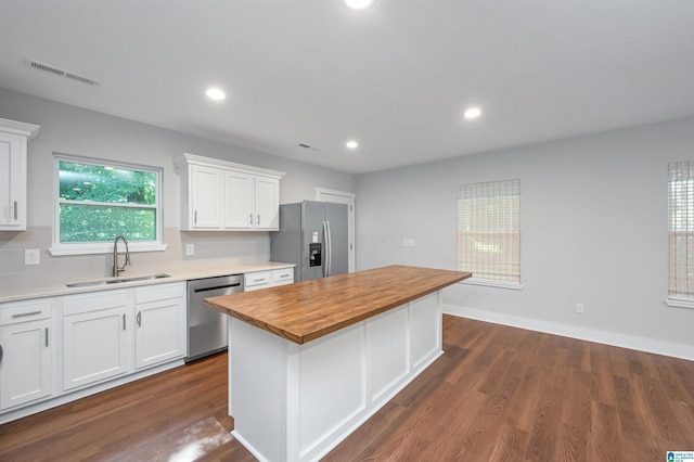 kitchen with butcher block counters, sink, appliances with stainless steel finishes, a kitchen island, and white cabinets