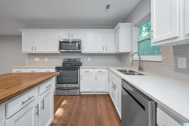 kitchen featuring sink, white cabinets, decorative backsplash, stainless steel appliances, and dark wood-type flooring