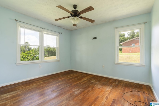 empty room with a healthy amount of sunlight, a ceiling fan, baseboards, and hardwood / wood-style floors