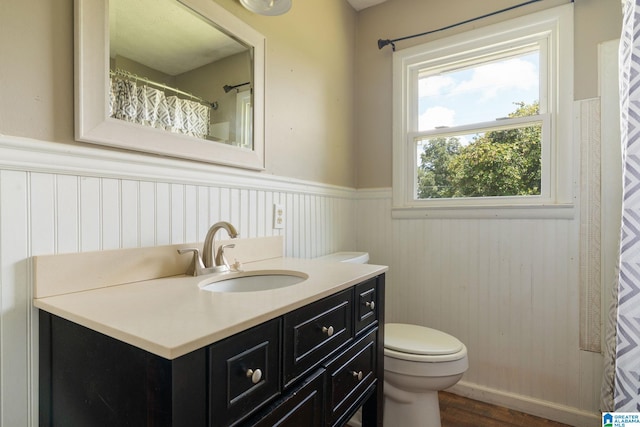 bathroom featuring wainscoting, vanity, toilet, and wood finished floors