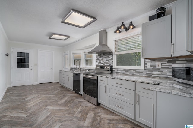 kitchen with tasteful backsplash, wall chimney range hood, parquet floors, stainless steel appliances, and crown molding