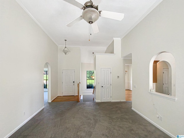 spare room with ornamental molding, carpet, ceiling fan, and a high ceiling