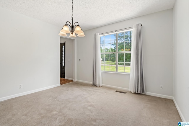 empty room featuring a textured ceiling, light colored carpet, and an inviting chandelier