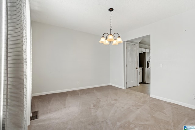 carpeted empty room featuring a notable chandelier