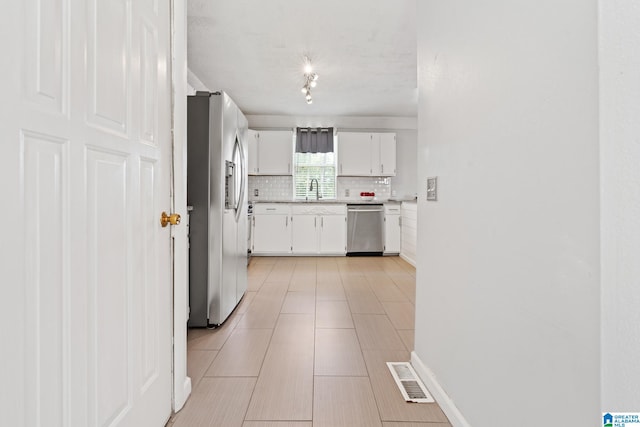 kitchen with tasteful backsplash, sink, white cabinets, and appliances with stainless steel finishes