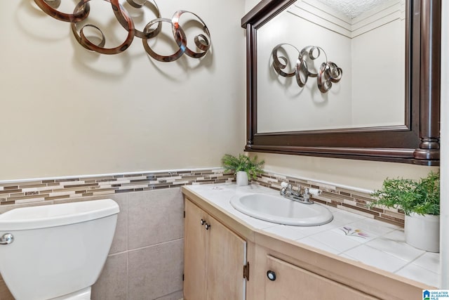 bathroom featuring vanity, toilet, and tile walls