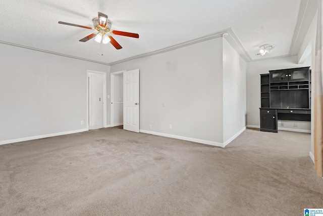 carpeted spare room with ceiling fan, a textured ceiling, and ornamental molding